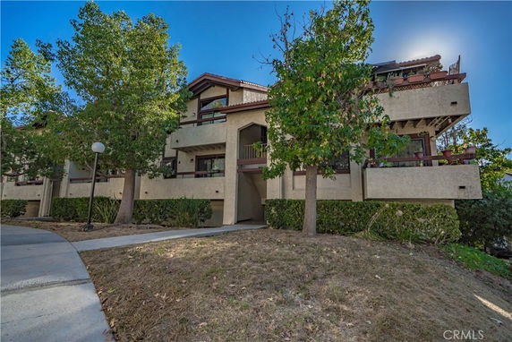 Front view of a multi-story residential building with balconies and trees around.