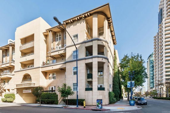 Front view of a multi-story building with balconies and arched entryway.