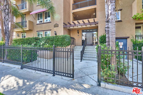 Front view of a multi-story building with balconies and an entrance gate.