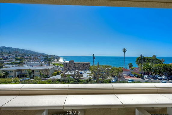 Panoramic ocean view from a balcony or terrace with surrounding buildings and trees.
