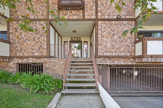 Front view of a multi-story building with a brick facade and central entrance stairs.