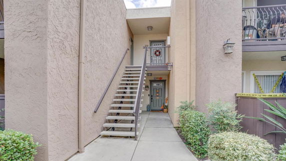 Exterior view of a multi-unit building entrance with stairs leading to the upper level.