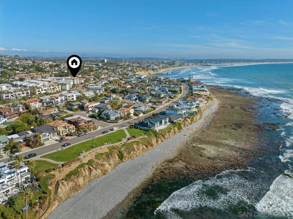 Panoramic aerial view of a coastal residential area with houses and the ocean.