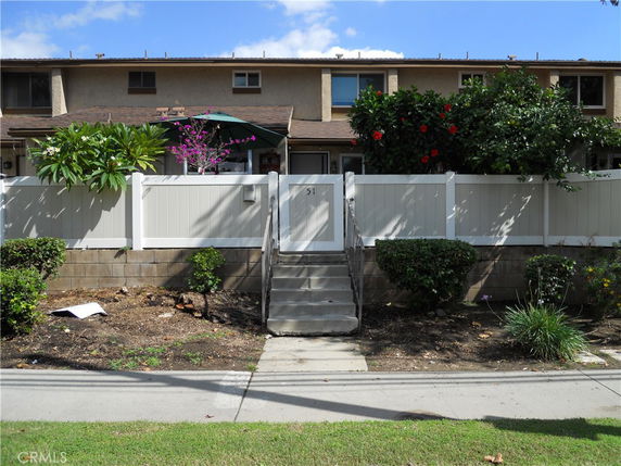 Front view of a two-story building with a white fence and a small garden.