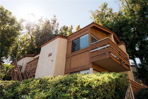 Front view of a two-story house with balconies and wood paneling.