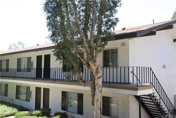 Front view of a two-story residential building with balcony and exterior staircase.