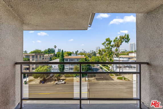 View of surrounding buildings and trees from a balcony with railing.