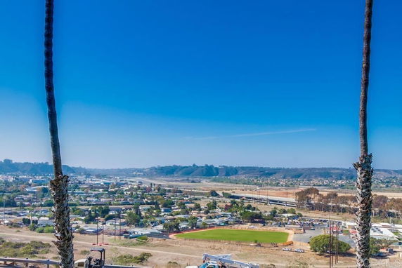 Panoramic view of a residential area with a baseball field and distant hills.