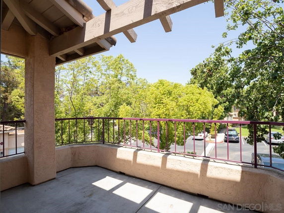 View from a balcony with trees and parking area visible in the background.