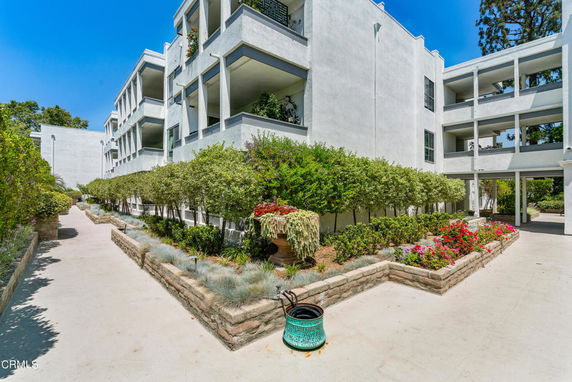 Front view of a multi-story apartment building with balconies and landscaped pathways.