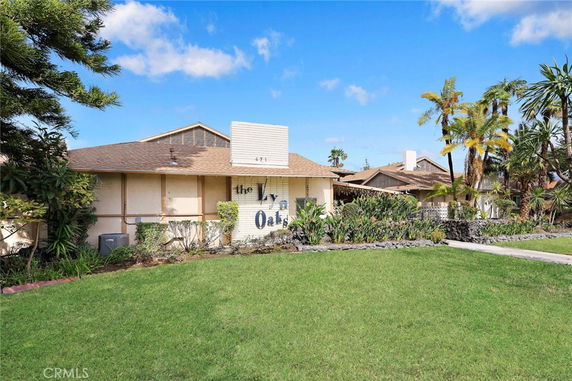 Front view of a single-story house with a pitched roof and decorative plants.
