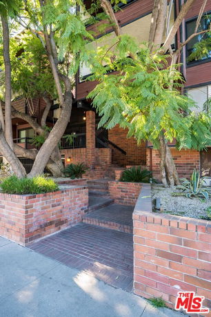 Front view of a multi-story building with a brick facade and surrounding trees.