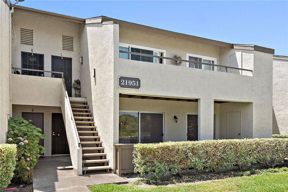 Front view of a two-story building with an exterior staircase and multiple doors.