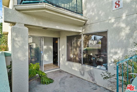 Front view of a building with a balcony, sliding door, and a large window.