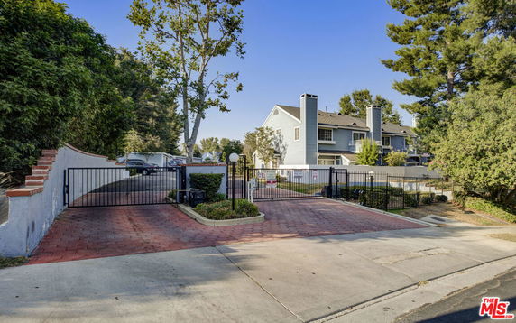 Front view of a multi-story house with chimneys and gated entrance.