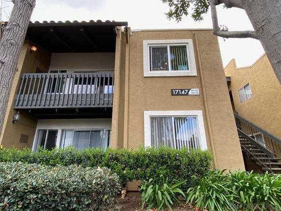 Front view of a two-story apartment building with beige exterior and balconies.