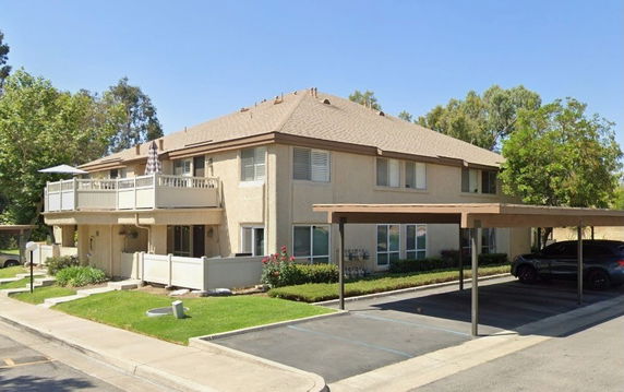 Front view of a two-story residential building with attached balconies and covered parking.