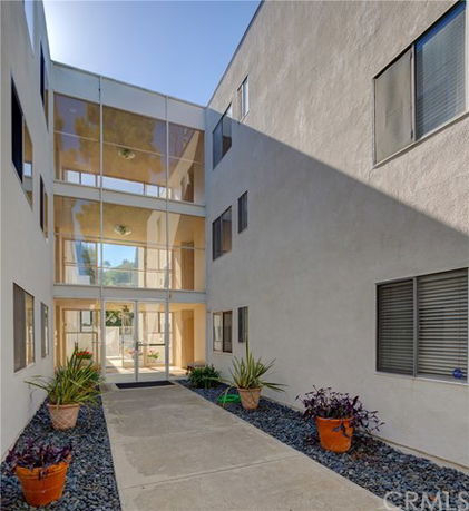 Front view of a multi-story apartment building with glass entryway.