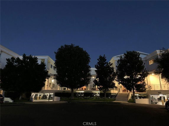 Front view of a multi-story building with balconies and outdoor lighting at night.