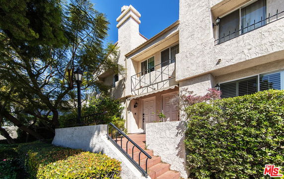 Front view of a multi-story house with a balcony and entrance steps.