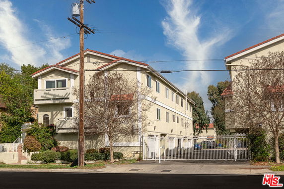 Front view of a multi-story residential building with a gated entrance.