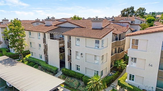 Front view of a multi-story residential building with balconies and a tiled roof.