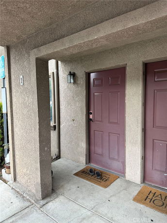 Front view of a building with beige stucco walls and two brown doors.