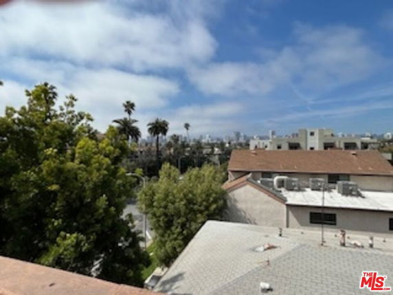 Panoramic view over rooftops with city skyline in the distance.