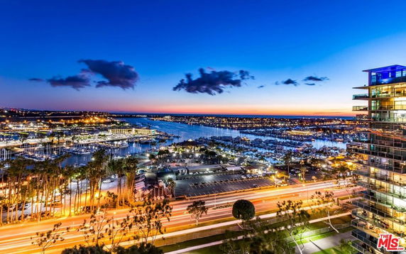 Panoramic view of a cityscape with water body and marina at dusk.