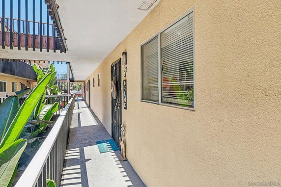 Exterior view of an apartment corridor with beige walls and railing.
