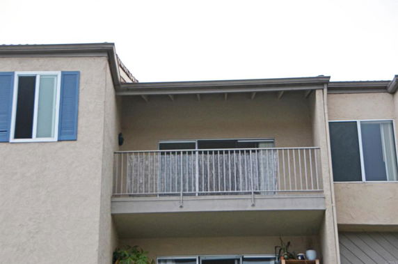 Front view of a multi-story building with balcony and windows.