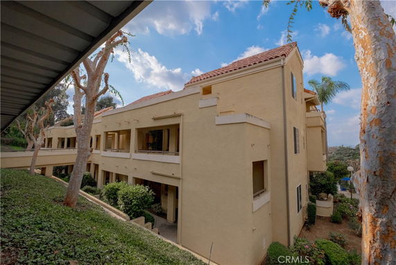 Side view of a multi-story residential building with balconies and a red tile roof.