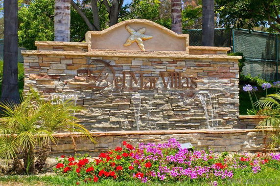 Stone wall with the name 'Del Mar Villas' and decorative water feature.