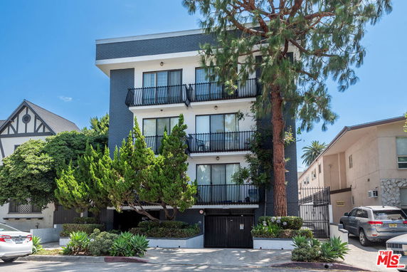 Front view of a multi-story apartment building with balconies and a gated entry.