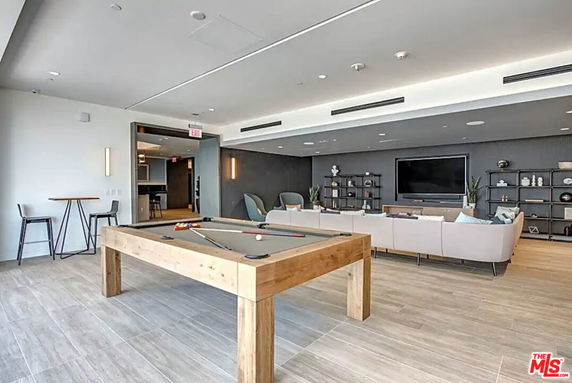 Common area with a billiards table, seating, and a television.