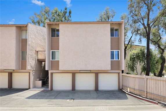 Front view of a multi-story residential building with garages on the ground level.