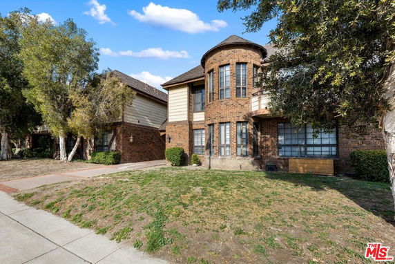 Front view of a two-story brick house with large windows.
