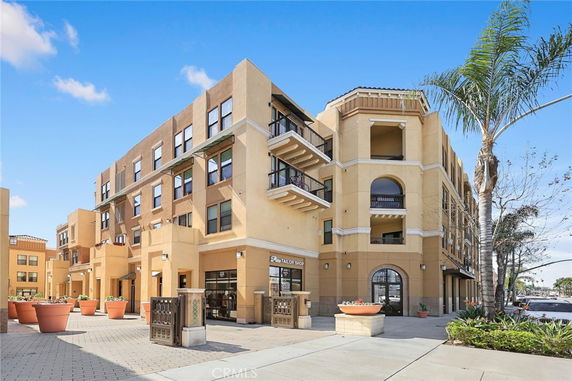 Front view of a multi-story building with balconies and commercial spaces on the ground floor.