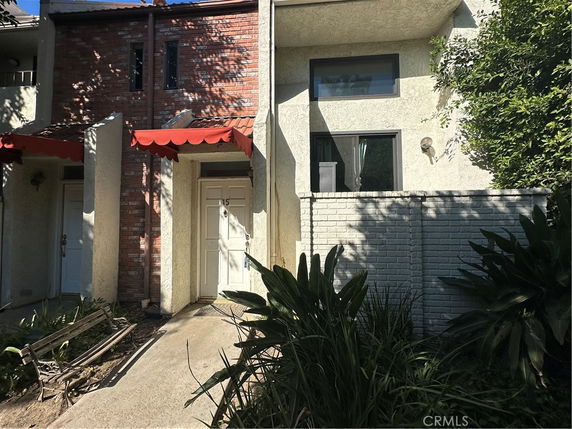 Front view of a two-story house with red awnings and white doors.