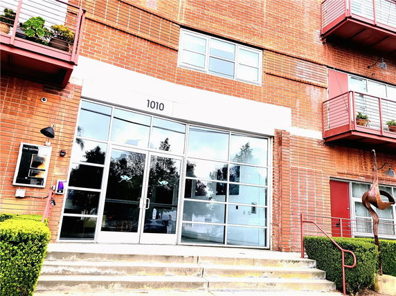 Front view of a brick multi-story building with balconies and large glass entrance doors.