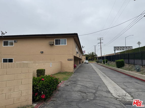 Side view of a two-story beige building with parking area and driveway.