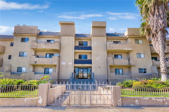 Front view of a multi-story residential building with balconies and a gated entrance.