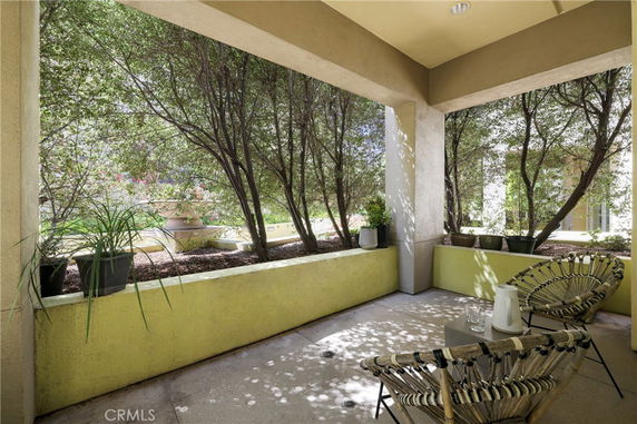 Outdoor patio area with chairs and plants, surrounded by greenery.