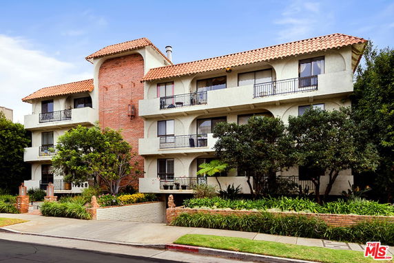 Front view of a three-story building with balconies and a brick facade.