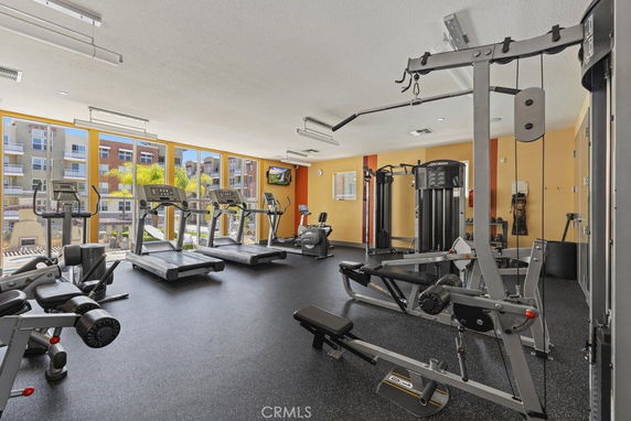 Indoor gym area with various exercise equipment and large windows.