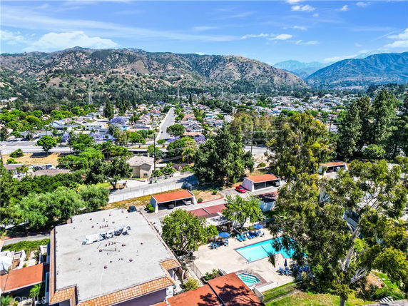 Aerial view showcasing a residential area surrounded by mountains and greenery.
