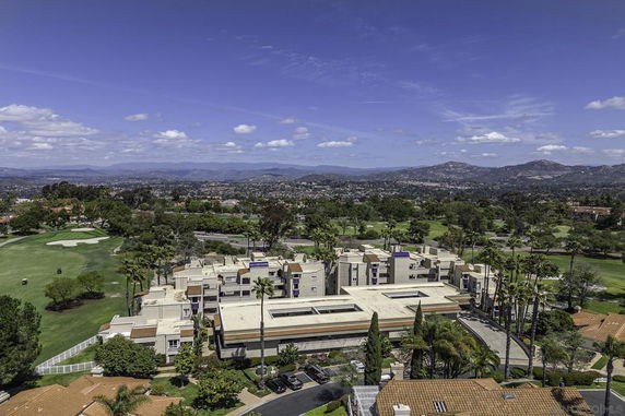 Panoramic view of a building complex with golf course and mountains in the background.