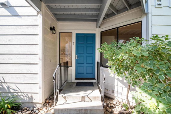 Front view of a house entrance with a blue door and metal railings.