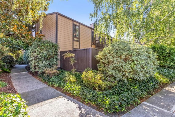 Front view of a two-story house with a wooden exterior and surrounding greenery.