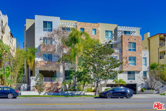 Front view of a multi-story modern apartment building with a mix of materials on the facade.